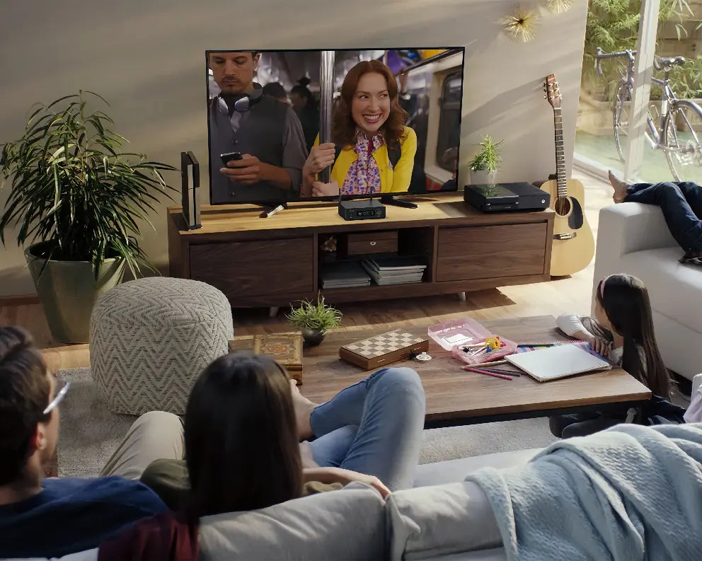 Family living room entertainment scene, watching movies together with Arylic audio amplifier on the TV cabinet, enhancing home theater sound experience.