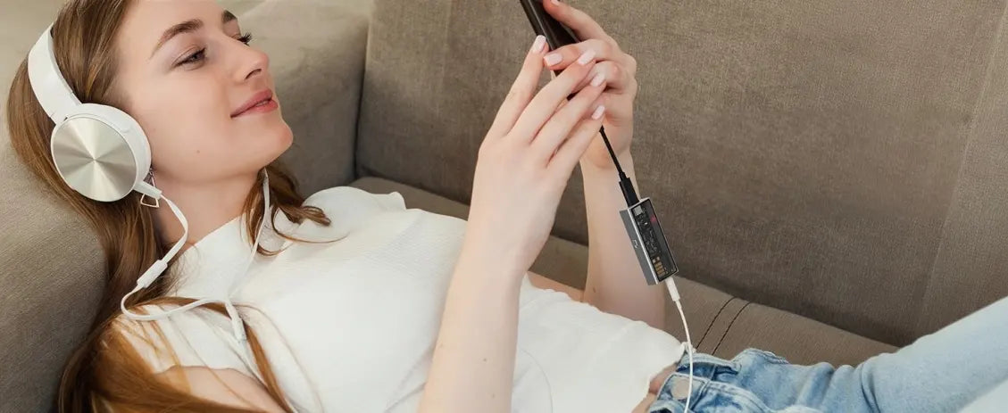 Woman using Questyle M15C portable DAC amplifier with smartphone and headphones